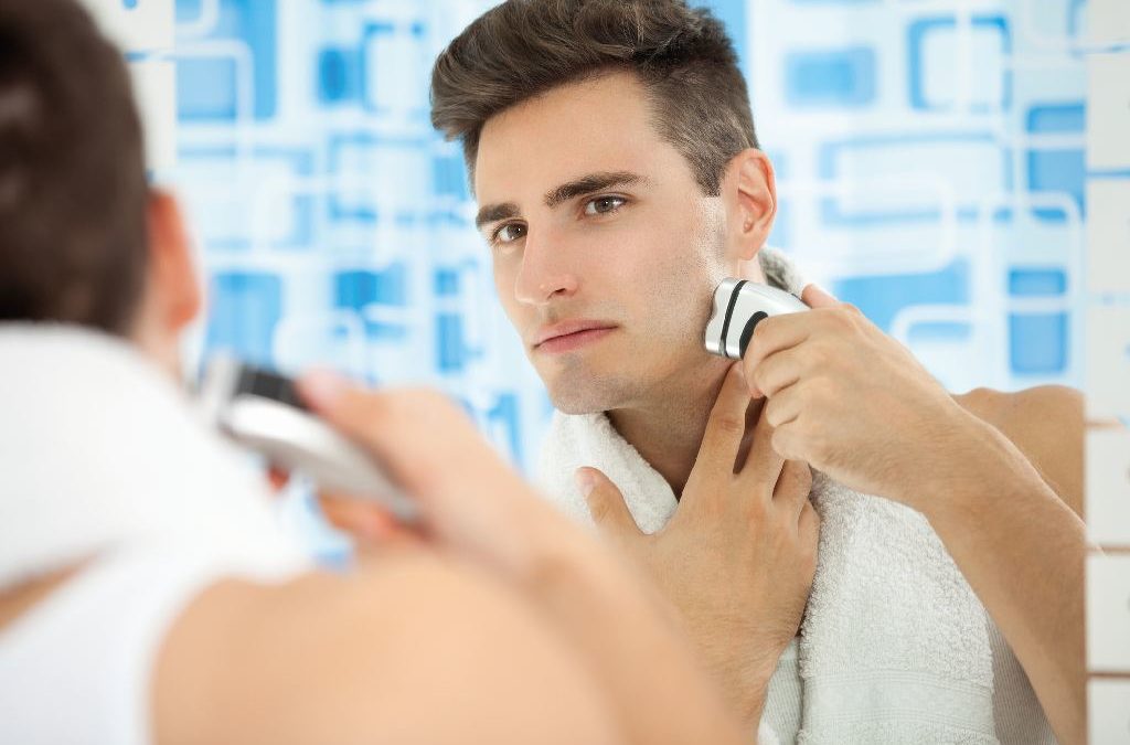 Junger Mann rasiert sich vor dem Spiegel (Haut)