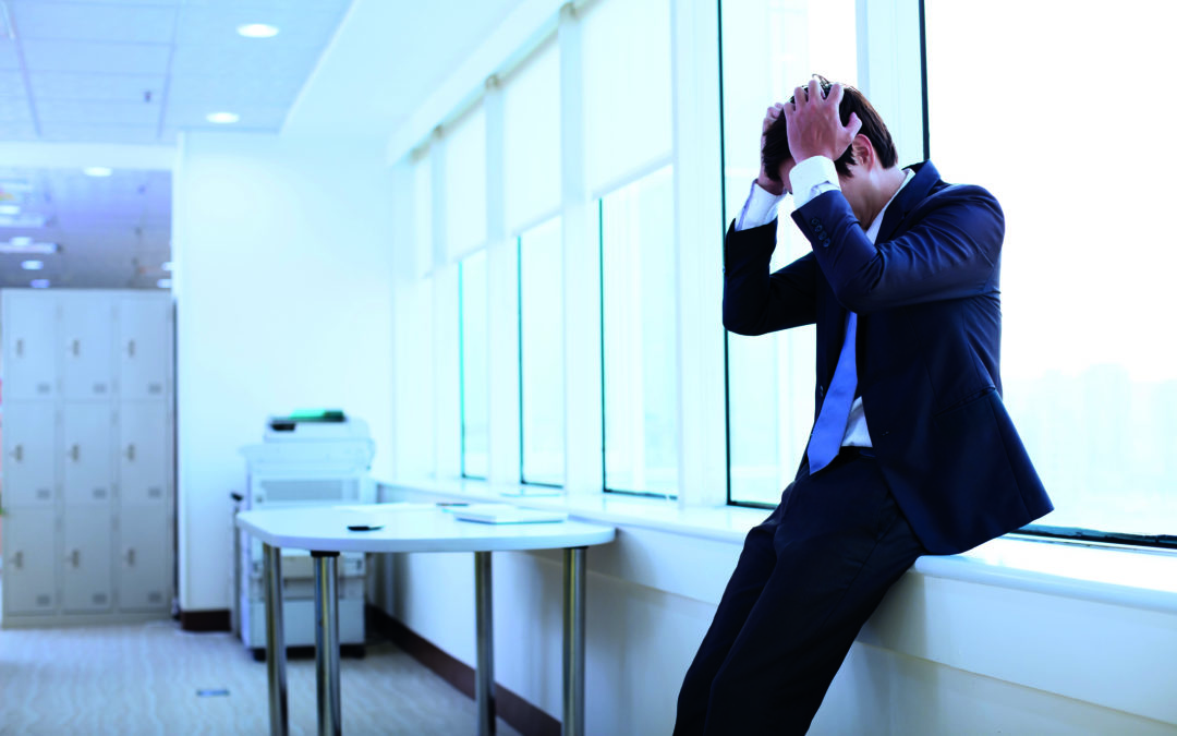 Schwitzen bei Stress: Ein Mann im Anzug schlägt die Hände über dem Kopf zusammen und ist gestresst