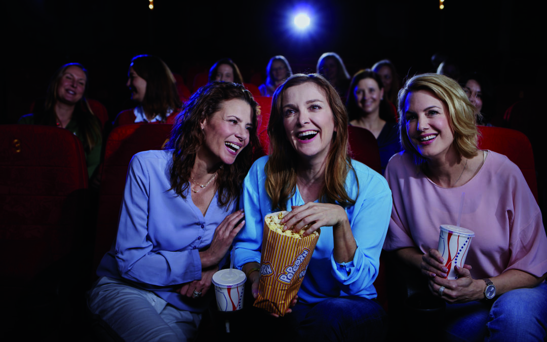 Drei Frauen genießen einen Kinobesuch, trotz Blasenschwäche
