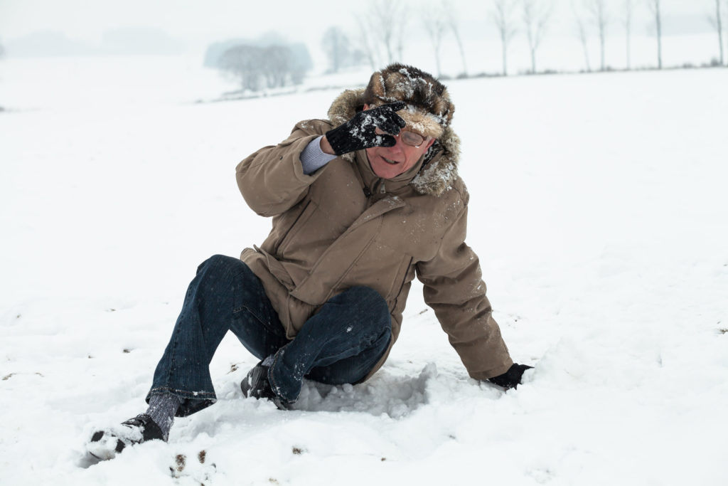 Ein älterer Herr ist im Schnee gestürzt – besonders bei Osteoporose ein Verletzungsrisiko.